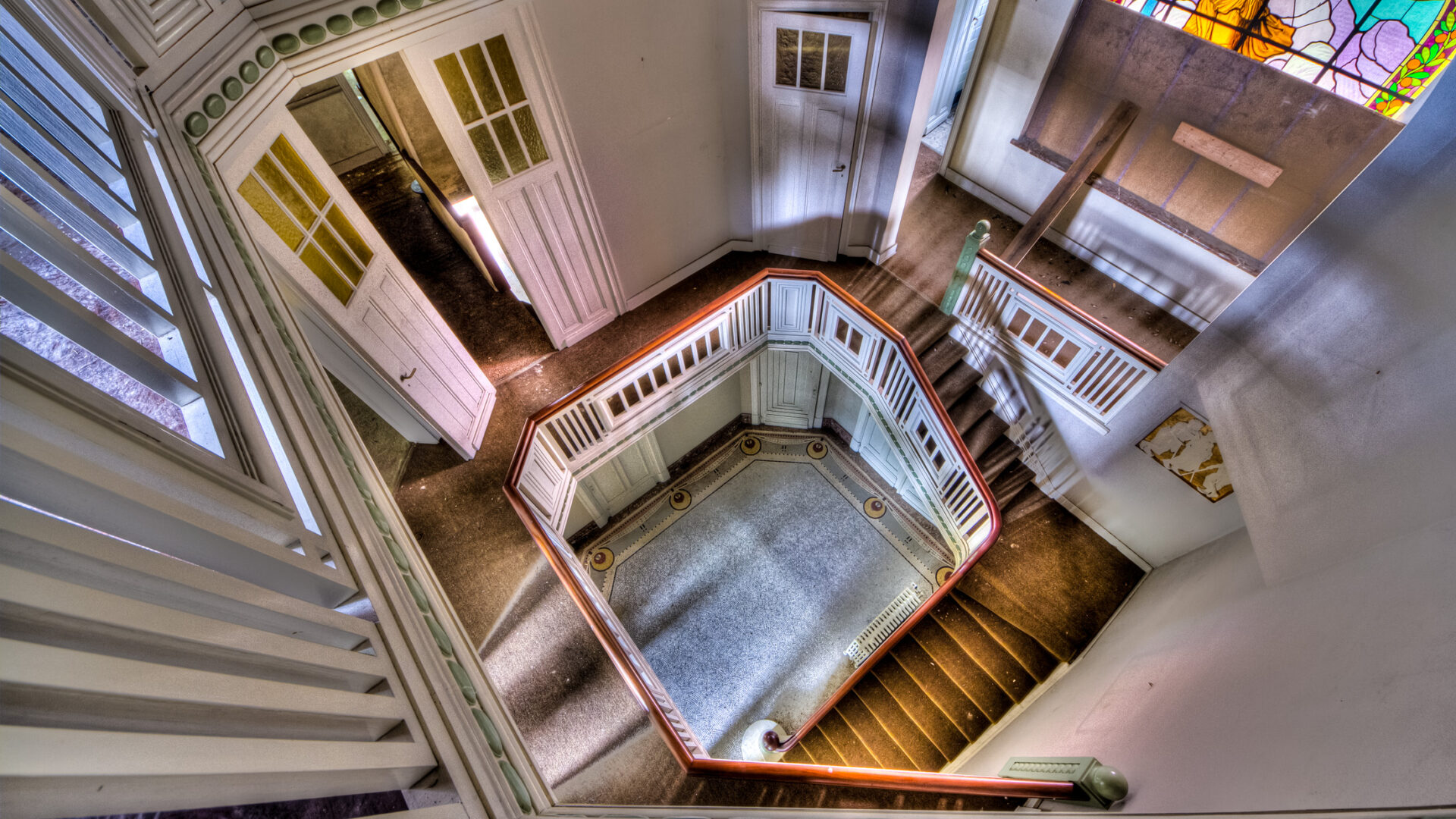 Decaying elegance: Abandoned villa staircase in Belgium, showcasing bygone opulence and neglect.