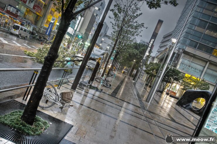 Contemporary cityscape with wet sidewalks, modern buildings, and bustling streets in urban setting.