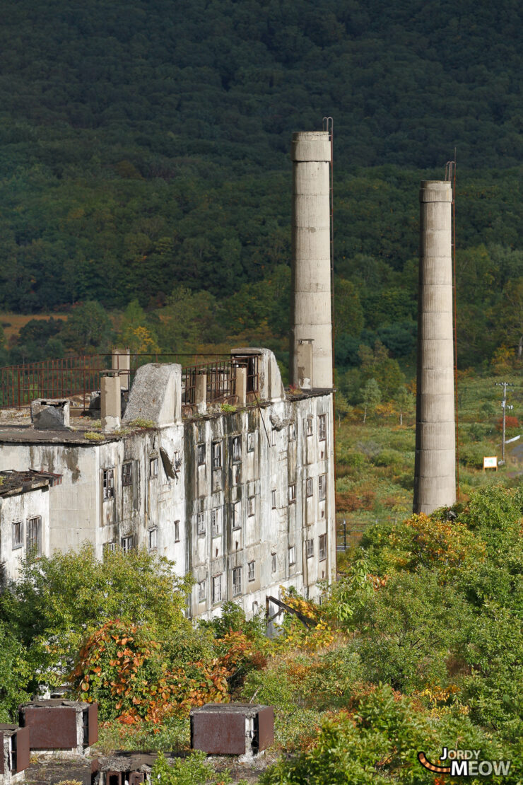 Forgotten Legacy: Matsuo Mine in Tohoku - Abandoned concrete structures amidst lush hills.