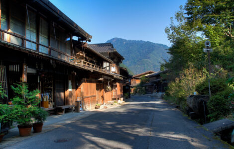 Tranquil Japanese village with traditional wooden buildings nestled in lush green mountains.