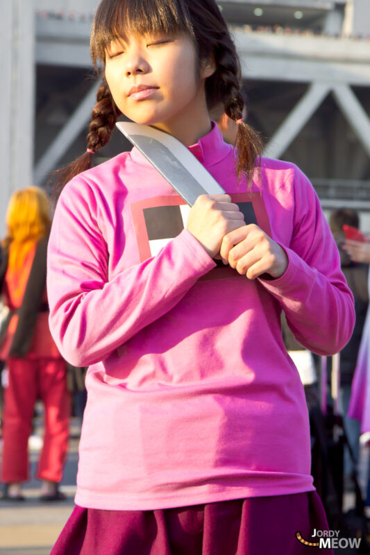 Japanese girl in pink sweater on Tokyo stage embodies traditional culture with braided hair.