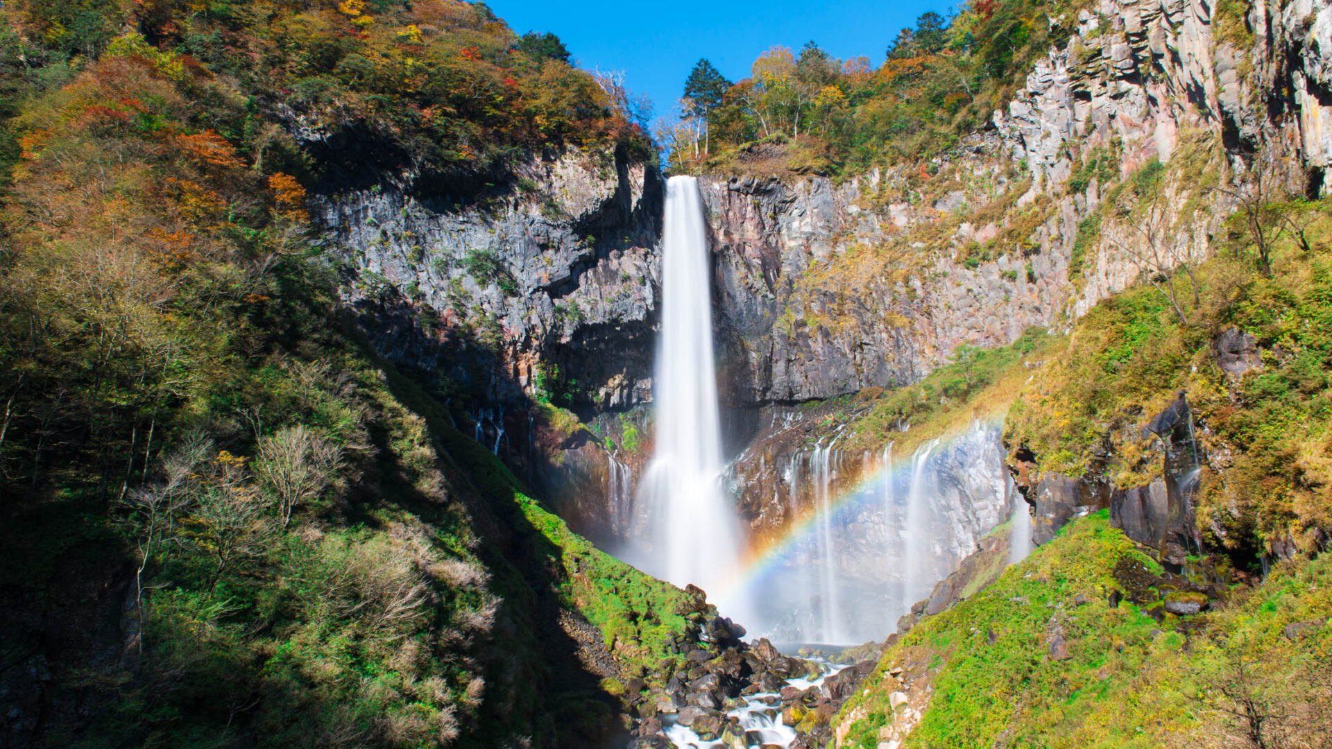 Enchanting autumn waterfall with rainbow and vibrant foliage, creating a mesmerizing display of beauty.
