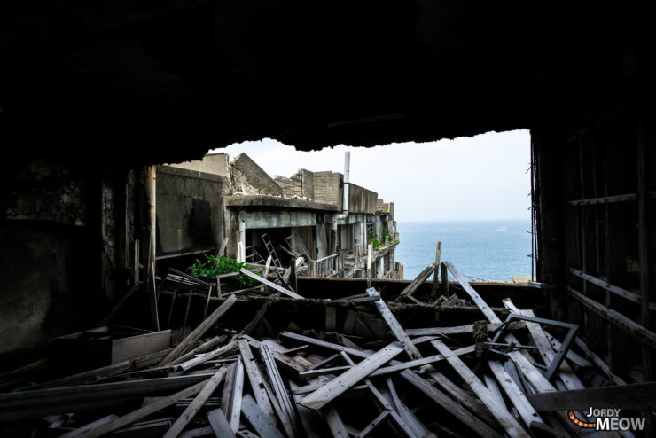 Exploring abandoned Gunkanjima Island apartments: a scene of desolation against a serene sea.