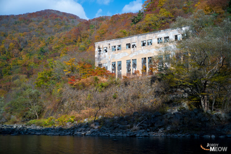 Abandoned Wagakawa Hydro Plant surrounded by vibrant autumn foliage in Tohoku, Japan.