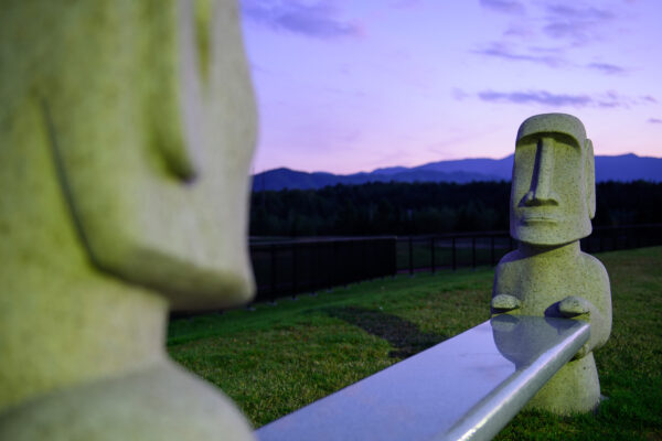 Enigmatic Moai statues in Hokkaido, creating a striking contrast with lush green hills.