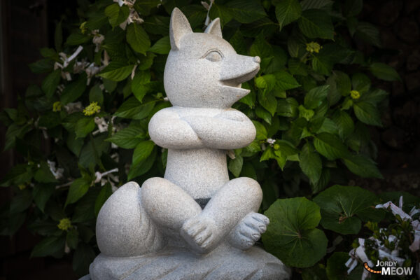 Tranquil Japanese shrine with fox statue and red torii gates in Nagato City.