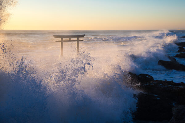 Majestic torii gate amidst crashing waves and rugged cliffs at Oarai Isosaki Shrine.