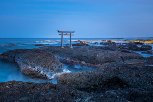 Tranquil Oarai Isosaki Shrine with torii gate on rocky reef in Japan.