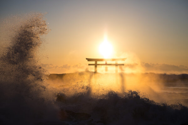 Majestic Oarai Shrine: Iconic torii gate on reef, embraced by waves at sunset.