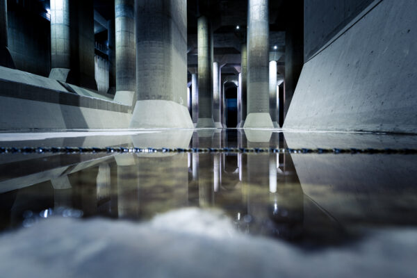 Subterranean Water Discharge Channel with dramatic lighting and towering concrete columns.