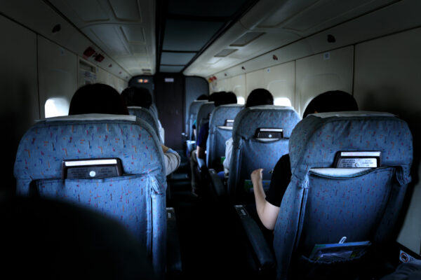 Airplane interior during flight to Chofu, passengers seated in blue-patterned seats.