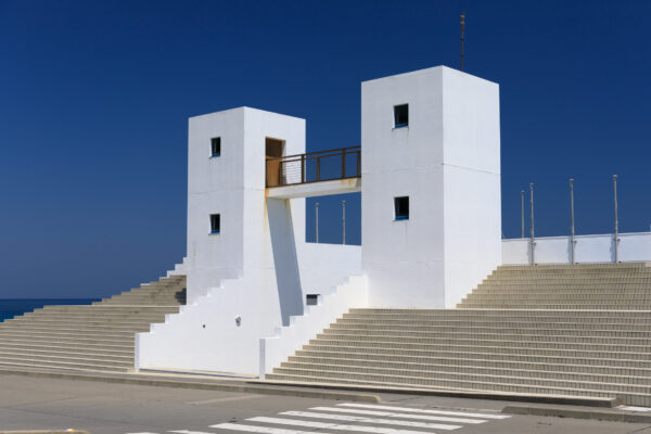 Modern white towers overlooking turquoise ocean at Habushiura Coast, harmoniously blending architecture and nature.