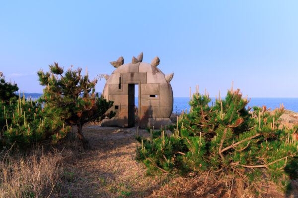 Enigmatic stone sculptures on Niijimas coast invite exploration amidst lush vegetation and rugged terrain.