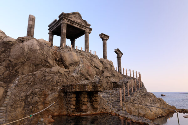 Majestic ancient architecture of Yunohama Roten perched on rocky outcrop overlooking the sea.