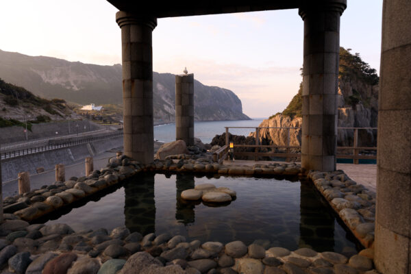 Seaside escape at Yunohama Roten onsen, overlooking ocean and Greek architecture.