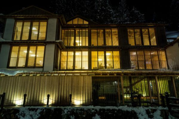 Enchanting Japanese hot spring resort in snow-covered mountains at night.