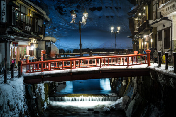 Charming winter scene with wooden bridge and traditional ryokans in Ginzan Onsen, Japan.