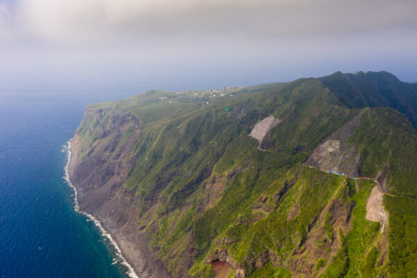 Aogashima: Remote volcanic island showcasing dramatic cliffs, lush vegetation, and imposing crater.