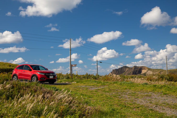 Vibrant red car on grassy path, Rebun Island scenery