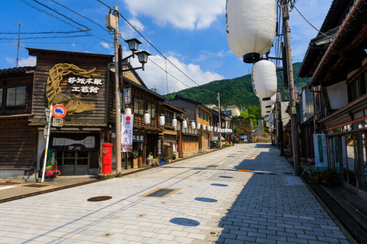 Charming Japanese street scene in Inami with wooden buildings, cobblestones, and mountains.
