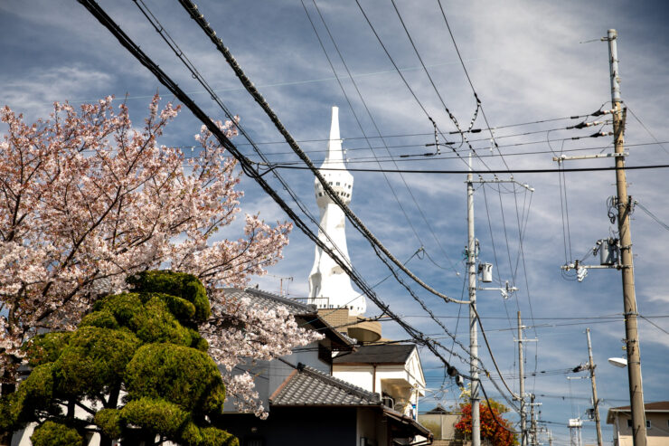 Towering spire memorializing fallen soldiers amid cherry blossoms.