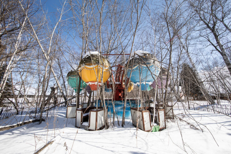 Abandoned whimsical playground structure in snowy landscape.