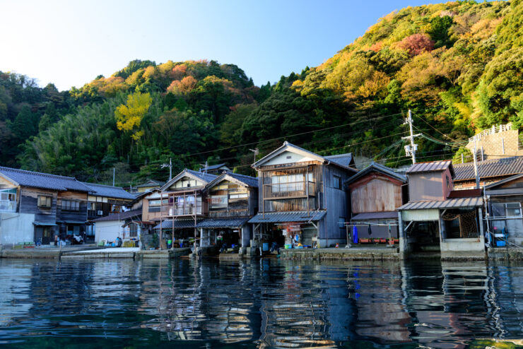 Serene Ine Boat Houses: Traditional Japanese village on calm waters with vibrant foliage.