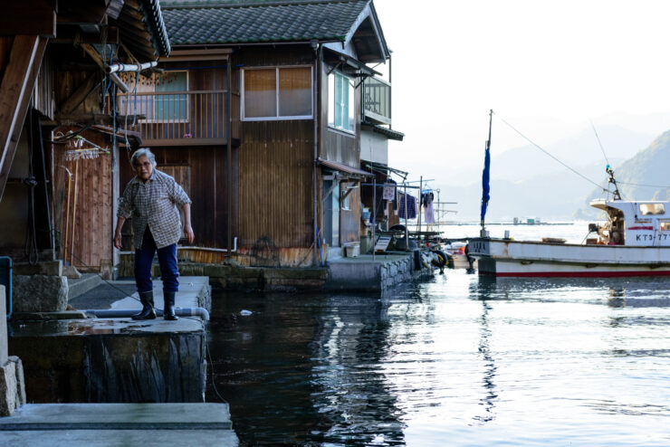 Tranquil boat houses on water in Ine Village, Japan, with mountains and reflections.