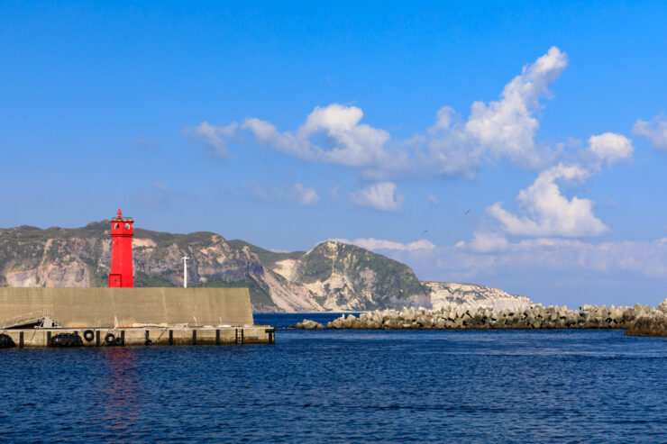 Shikinejima Islands iconic red lighthouse, scenic volcanic landscape.