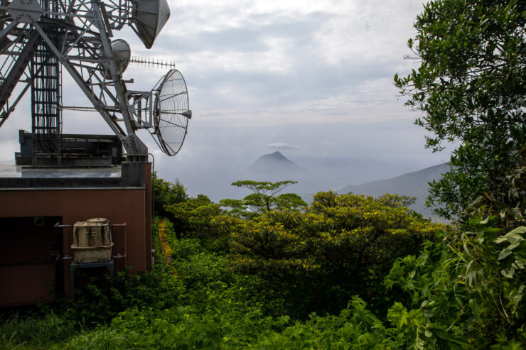 Telecom Tower Amidst Lush Greenery, Distant Mountains.