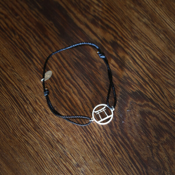 Earthy woven bracelet, metallic pendant, textured wood.