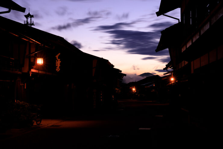 Lantern-lit traditional Japanese mountain village at dusk.