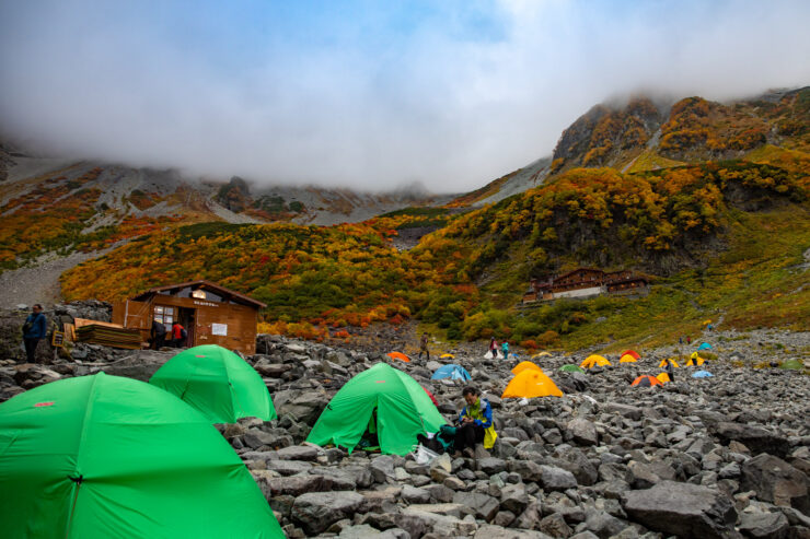 Autumn camping tents amidst vibrant mountain scenery.