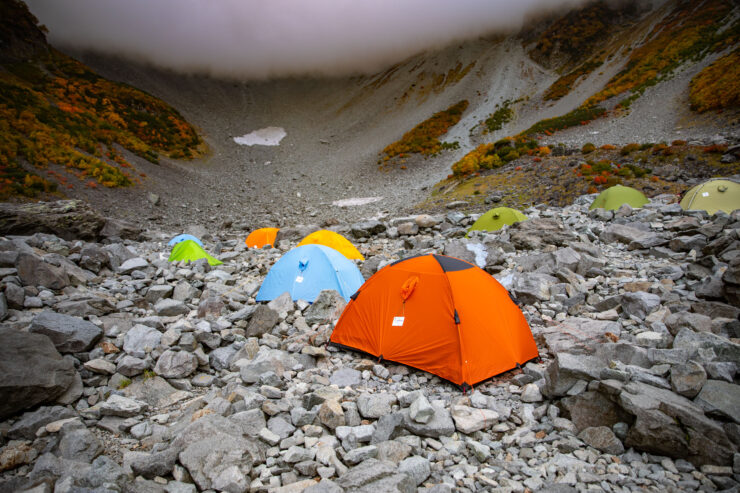 Vibrant tents amidst rugged mountain camping landscape.
