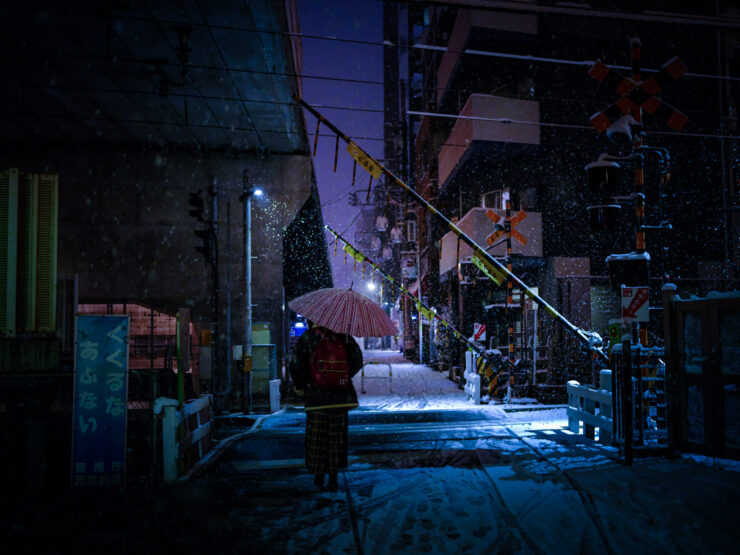 Urban night scene: Solitary walker in snowy alley.