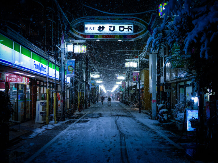 Illuminated snowy Japanese village street at night.