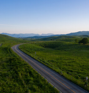 Akiyoshidai meadows, winding road, distant mountain landscape.