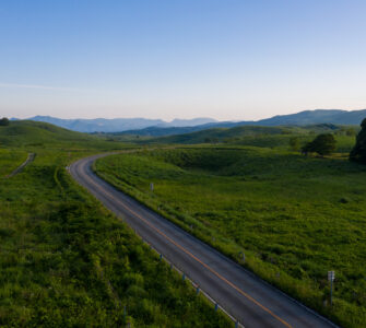 Akiyoshidai meadows, winding road, distant mountain landscape.