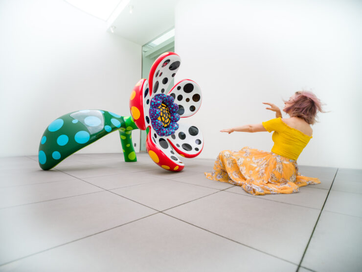Yayoi Kusamas vibrant interactive sculpture captivates child.