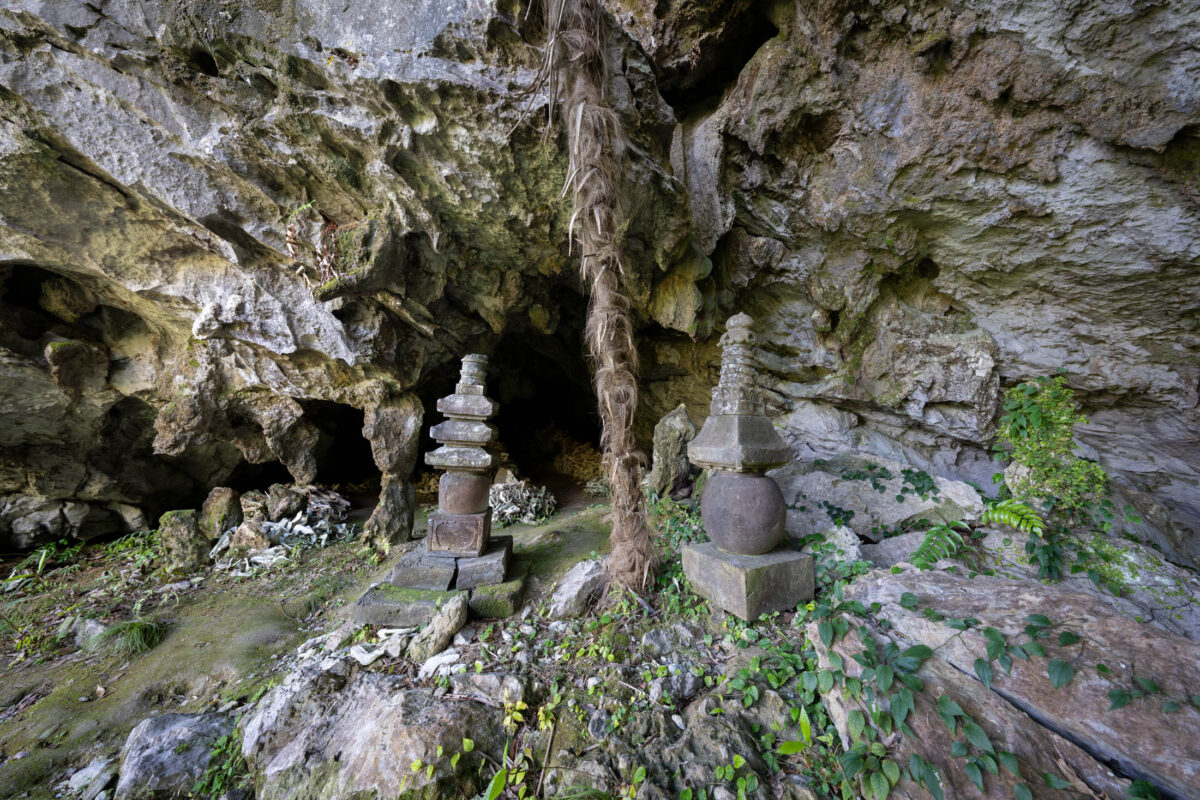 Shishi Gongen cave shrine with stone pagodas and sacred rope hanging from rocky ceiling