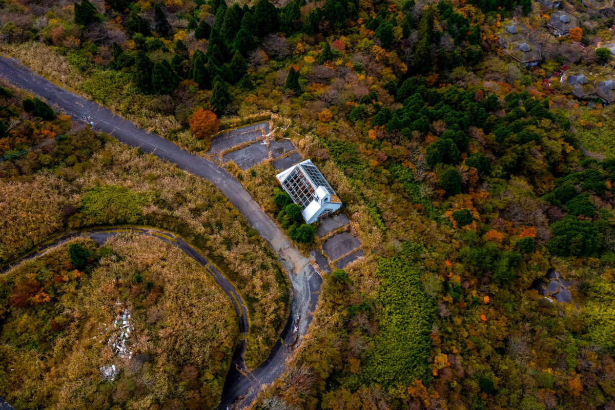 Aerial view of abandoned church surrounded by autumn forest and winding road