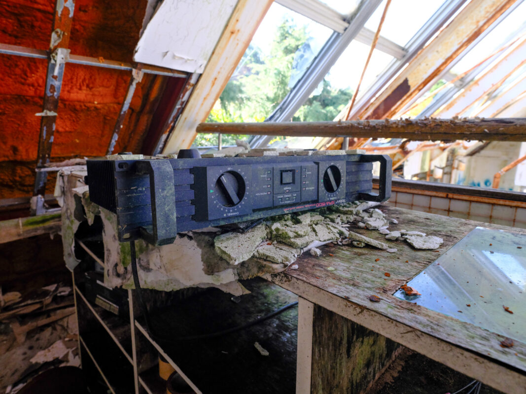 Sunlit abandoned church interior with broken roof, exposed beams, and dusty amplifier on loft.