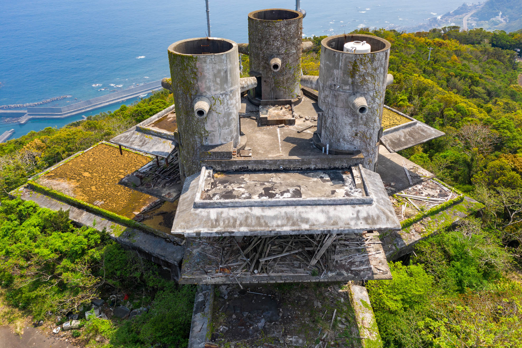 Aerial view of abandoned New Muroto Sky Resort concrete towers above Japan’s coastline