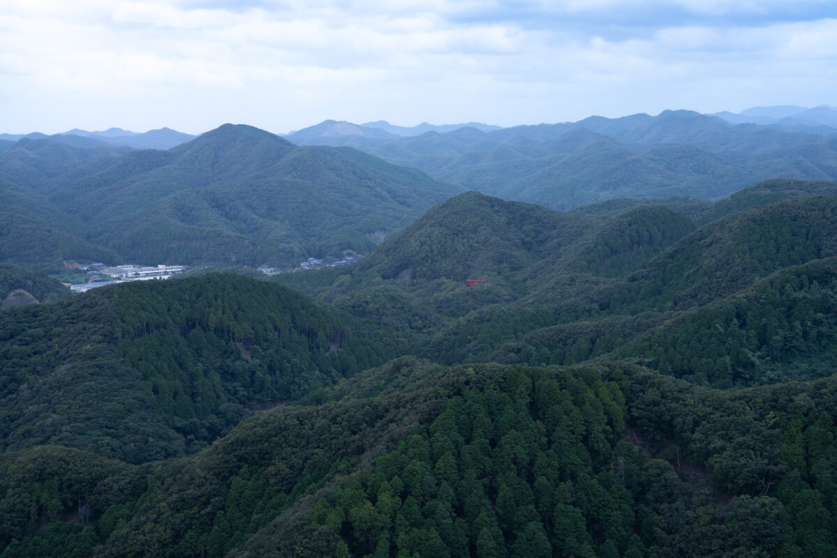 Panoramic Mount Eboshi view of layered forested mountain ridges under a cloudy sky.