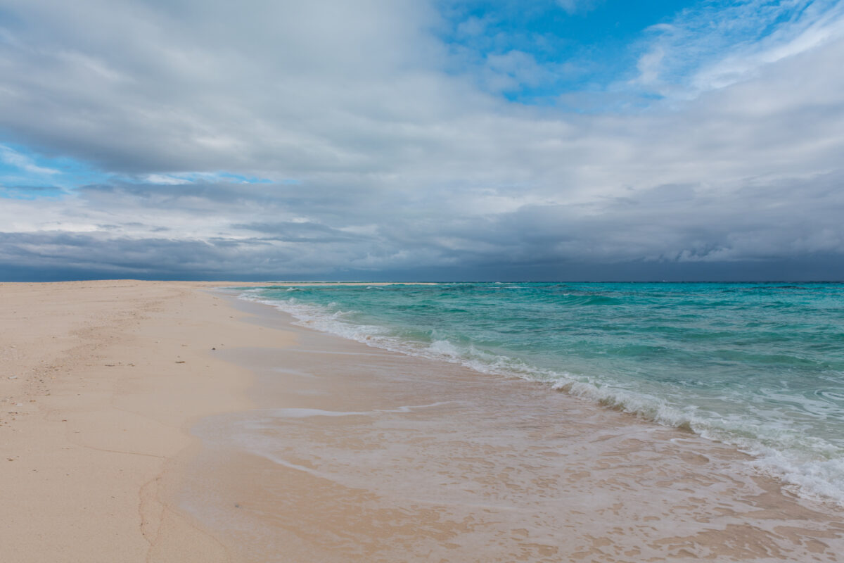 Turquoise waves on Kumejima Island beach under dramatic clouds, Okinawa Japan