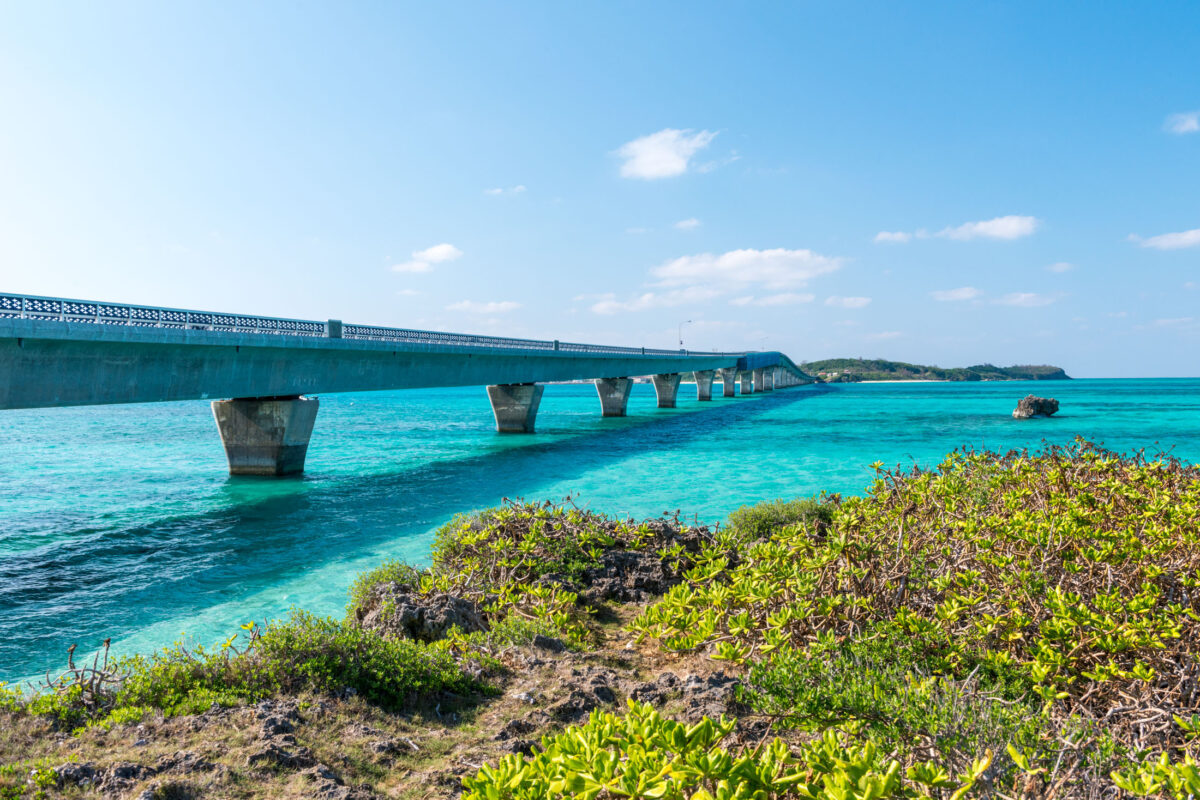 Miyako Island sea bridge curving over clear turquoise water under a bright blue sky.