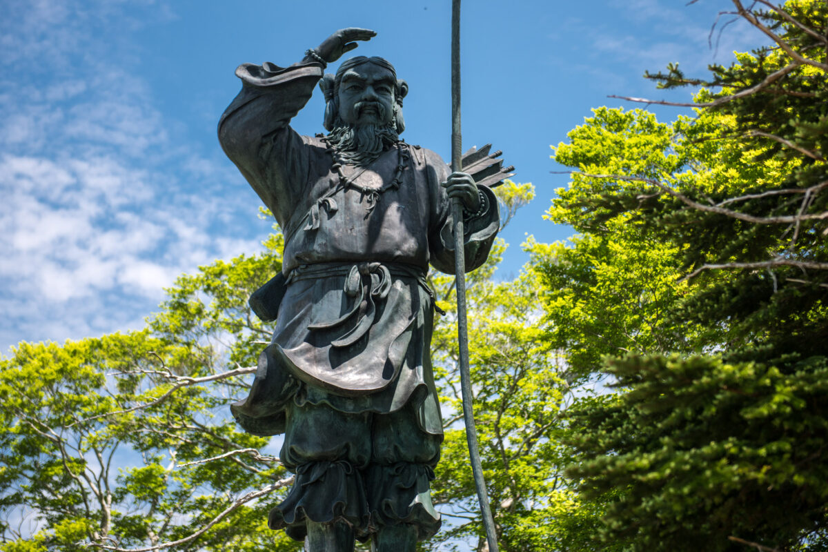 Weathered guardian statue with staff overlooking lush forest on Mount Ōdaigahara, Japan