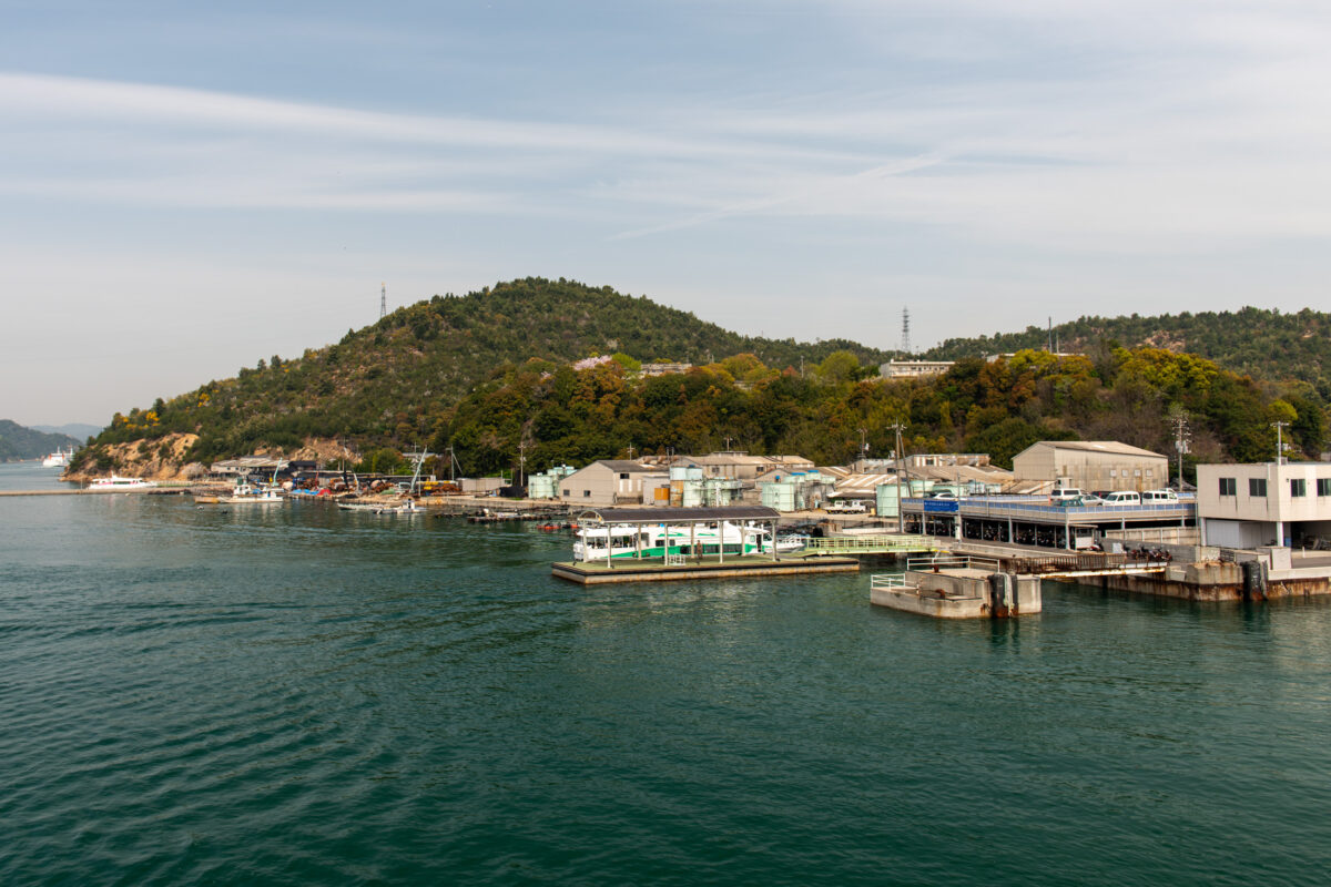 Naoshima Island harbor in Japan with calm sea, docks, and forested hillside
