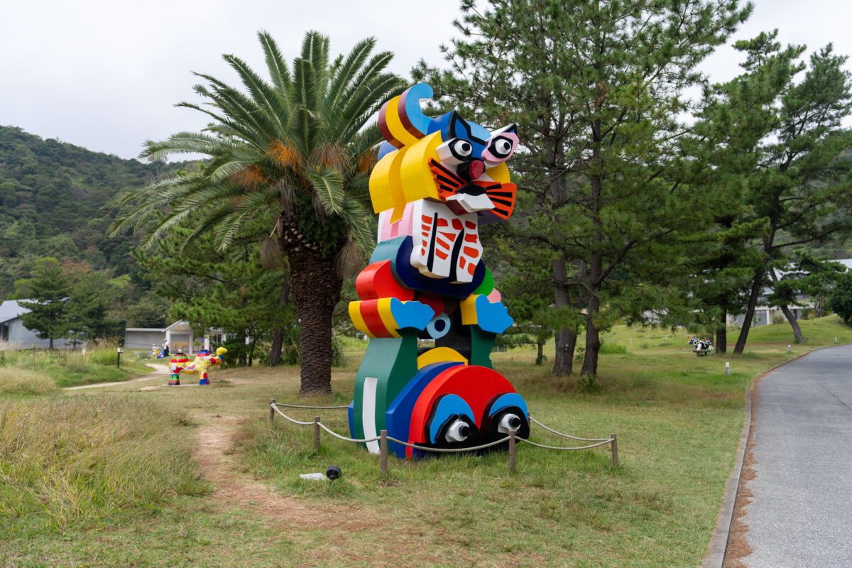 Colorful totem sculpture on Naoshima Art Island lawn beside curving path and trees