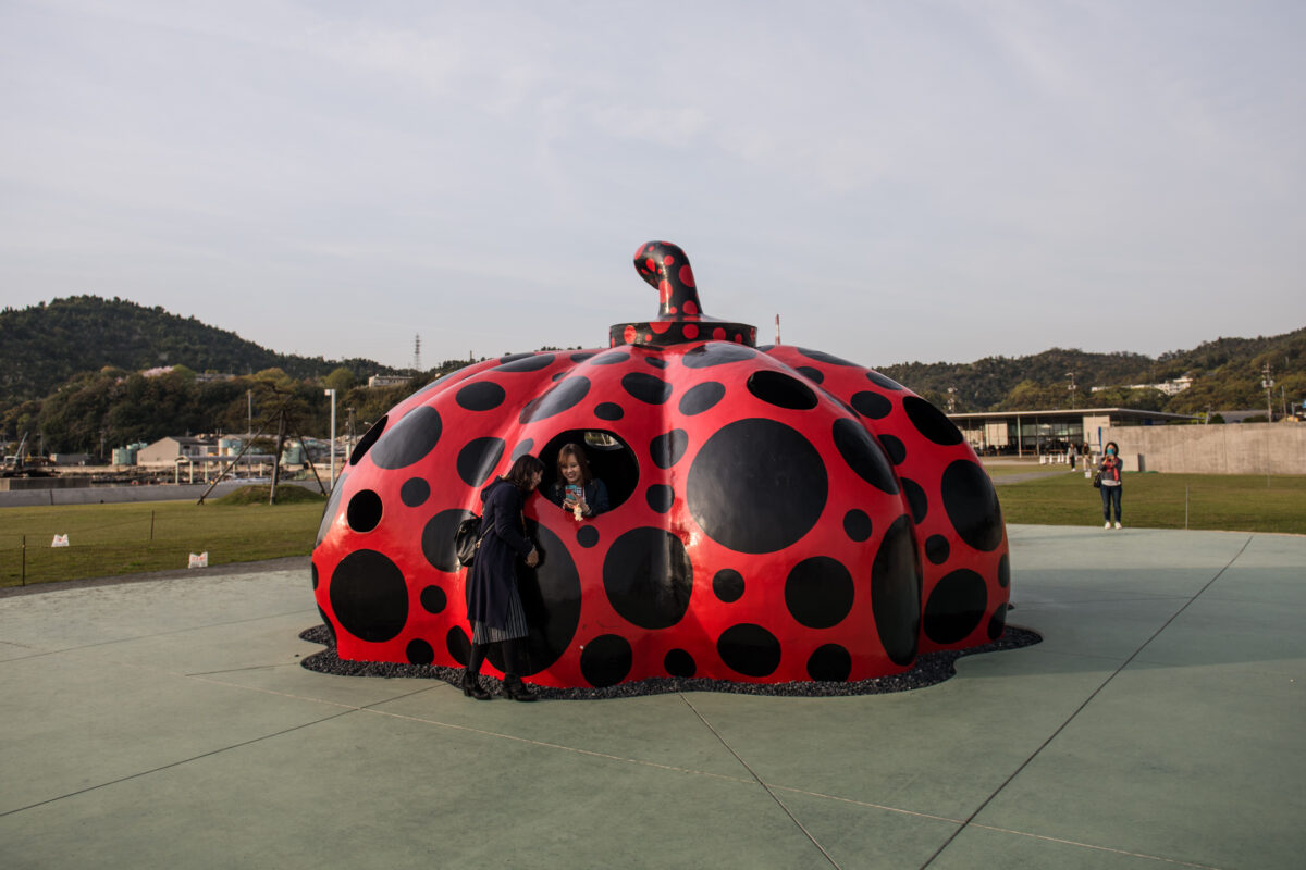 Visitors at Yayoi Kusama red polka-dot pumpkin sculpture on Naoshima Island, Japan.